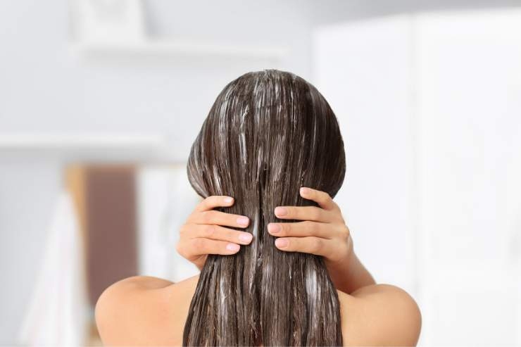 ragazza di spalle si fa lo sciampo